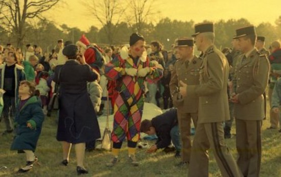 Le chef de corps accompagné de deux officiers recueille les impressions d'un clown à la combinaison ornée de losanges multicolores 